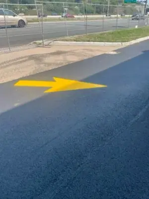 Close view of a yellow directional arrow on the asphalt.