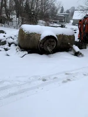 Cylindrical tank resting beside the excavation in snowy conditions.