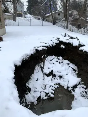 Open excavation with snow along the ground and exposed pipework.