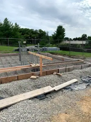 Timber forms, pipe risers, and aggregate base before concrete placement.