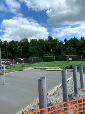 Newly placed concrete pad surrounding the pipe risers.