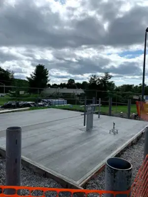 Newly placed concrete pad surrounding the pipe risers.