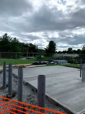 Newly placed concrete pad surrounding the pipe risers.