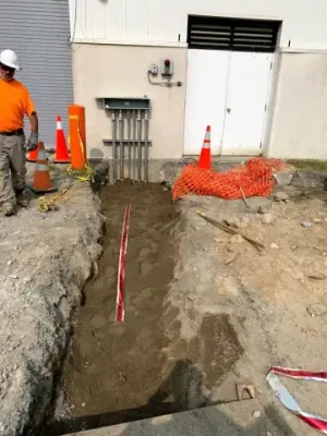 Conduit bank rising to electrical equipment on the facility wall.