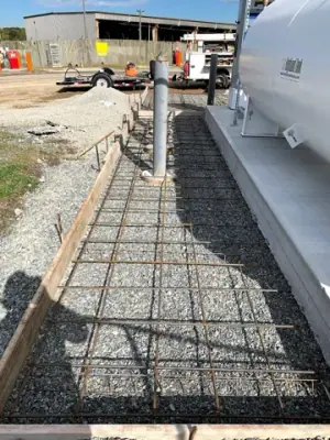 Protective posts and reinforced concrete forms alongside the installed tanks.