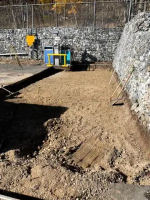 Excavated trench leading to the fueling equipment beside the retaining wall.