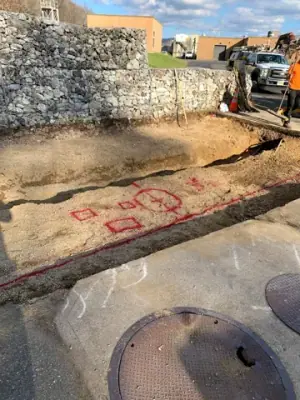 Open excavation and exposed service lines across the work area.