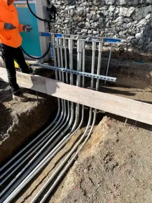 Parallel conduits and vertical risers within the prepared foundation area.