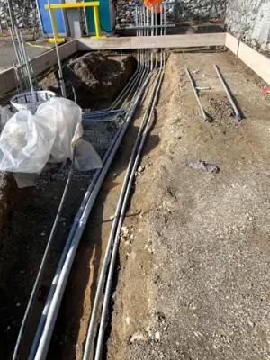 Parallel conduits and vertical risers within the prepared foundation area.