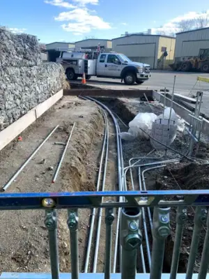 Parallel conduits and vertical risers within the prepared foundation area.