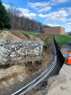 Conduit runs follow an open trench toward the facility building.
