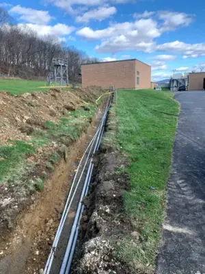Conduit runs follow an open trench toward the facility building.