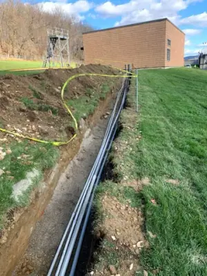 Conduit runs follow an open trench toward the facility building.