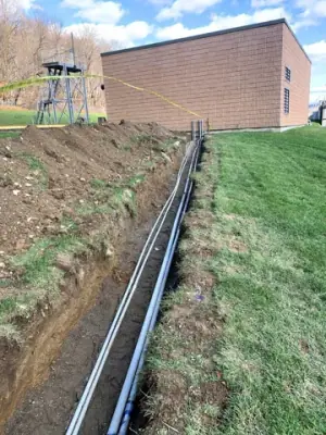 Conduit runs follow an open trench toward the facility building.
