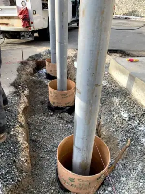 Protective steel posts set in excavated holes beside the concrete apron.