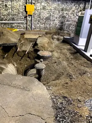 Excavation exposes tank-top access points and buried equipment.
