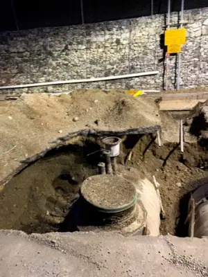 Excavation exposes tank-top access points and buried equipment.