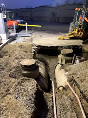 Excavation exposes tank-top access points and buried equipment.