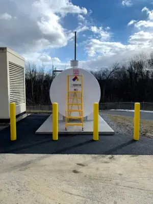 End of the aboveground tank with ladder and yellow protective bollards.