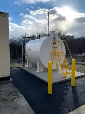 End of the aboveground tank with ladder and yellow protective bollards.