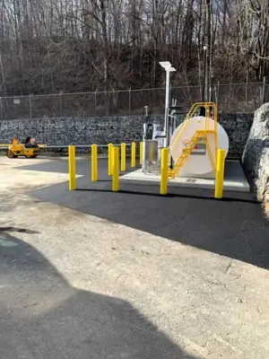 Fresh asphalt around the installed fueling equipment and protective bollards.