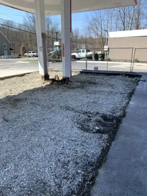 Removed forecourt pavement exposes aggregate around the fueling islands.