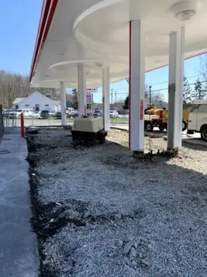 Removed forecourt pavement exposes aggregate around the fueling islands.