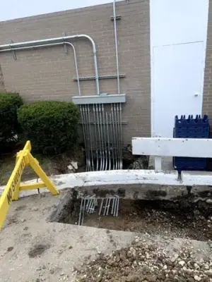 Excavation below the wall-mounted electrical conduit bank.