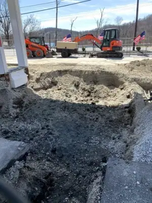 Excavated fueling-island area with open channels and earthmoving equipment.