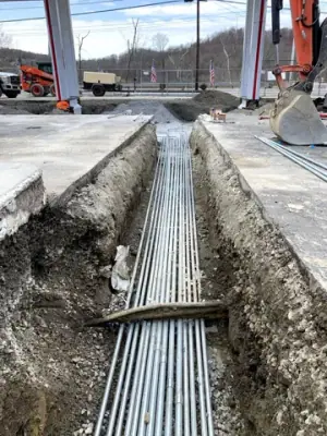 Parallel electrical conduits laid in an open trench beneath the forecourt.
