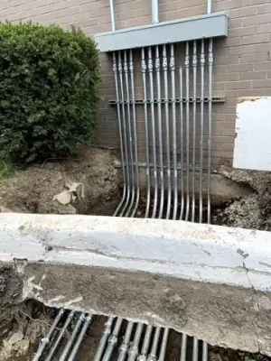 Conduits rise from the trench to the electrical equipment on the building wall.