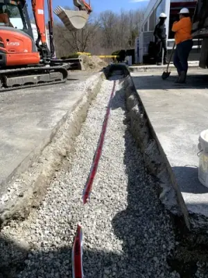 Gravel backfill and red warning tape along the utility trench.