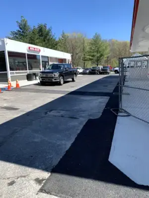 Dark asphalt strip alongside the concrete fueling apron.