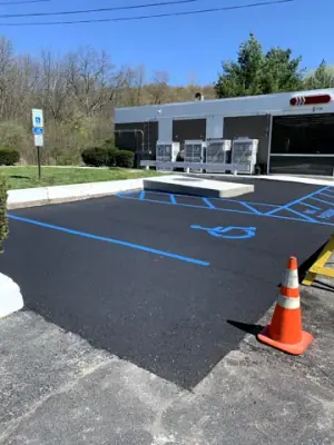 Blue accessible-parking lines and white space markings on fresh asphalt.