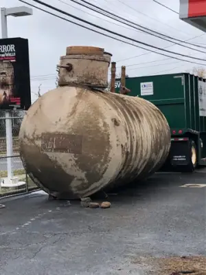 Removed cylindrical tank resting on the paved forecourt.