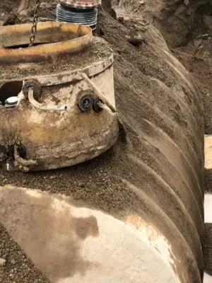 Tank-top access fittings exposed in the excavation.