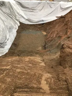 Excavation wall with protective sheeting draped along its edge.