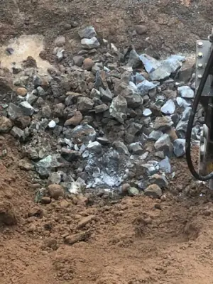 Broken rock accumulated in the excavated tank area.