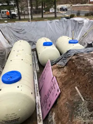 Multiple new underground tanks positioned side by side in the excavation.