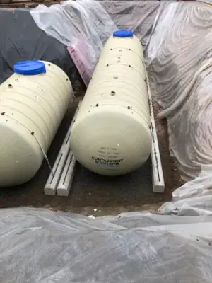 Multiple new underground tanks positioned side by side in the excavation.
