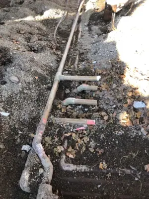 Existing pipework and fittings exposed along the trench.
