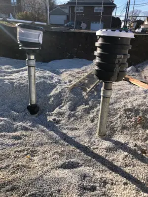 Tank risers and containment fittings projecting above aggregate bedding.