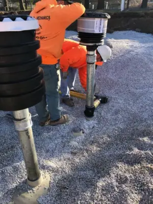 Technician working beside tank risers and containment fittings.