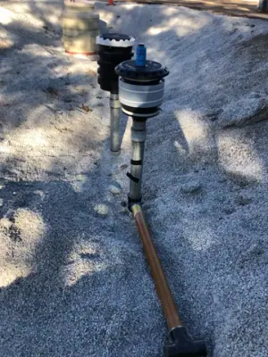 Close view of a tank riser assembly above the gravel surface.
