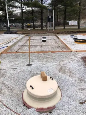 Round tank access fitting beside the prepared concrete pad.