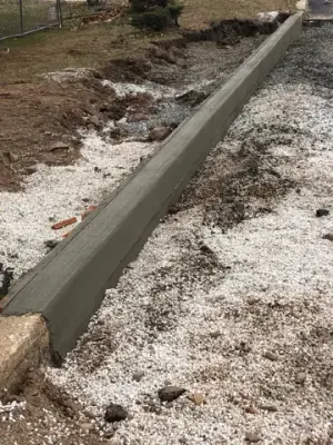 Narrow formed concrete curb beside the work area.