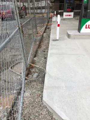 Temporary fencing separates the excavated edge from the concrete fueling lane.
