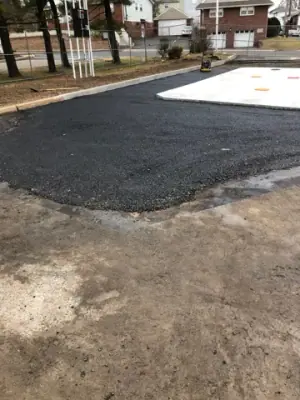 Fresh asphalt adjoining the concrete tank pad.
