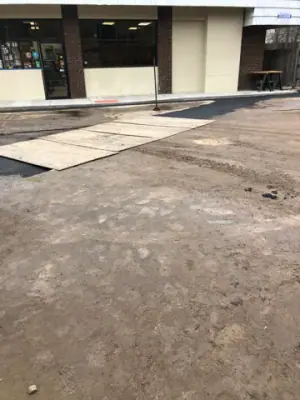 Concrete walkway and adjacent ground outside the shopfront.