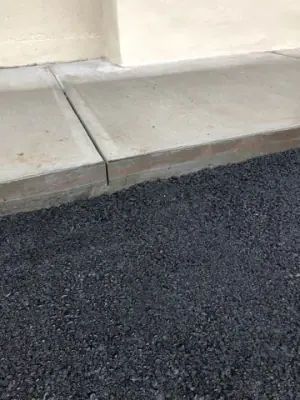 Close view of the asphalt-to-concrete walkway transition.